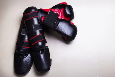 Black and red muay thai shin guard and boxing gloves