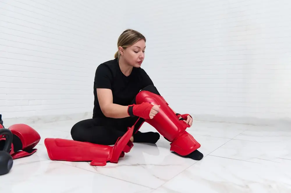 A girl is wearing red mma shin guard